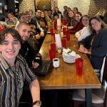 Members of the LIFT lab smiling around a long wooden dining table in a restaurant.